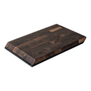 A rectangular Steelport Knife Co. SteelCore™ 2-in-1 Walnut Cutting Board (9"x6") with angled edges, showcasing a visible end-grain walnut pattern and a small engraved logo in one corner.