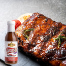 A glazed rack of barbecued ribs garnished with herbs on a dark surface, with a bottle of Hickman's BBQ Swinewaush No Sugar Added Gluten Free Natural BBQ Sauce 13 oz in front.