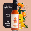 A bottle of Culture Hot Sauce Tangerine Dream is displayed alongside tangerines and peppercorns. The text highlights: clean ingredients, handmade, no added sugar. The label on the bottle features an orange handprint.