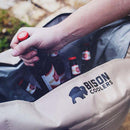 Sand cooler bag by Bison Coolers holding bottles with red caps.