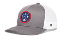 The Haka Hat Tennessee Trucker Hat, also known as the Black TEN X Football Snapback by Haka Hat, features a gray and white design with a round blue and red patch showing crossed lines, the letters T, E, N, and a small football. This Nashville football snapback offers classic style with its curved brim and white mesh back for comfort.