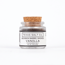 A small glass jar with a cork lid holds Texas Salt Co. Bourbon Barrel Smoked Vanilla Finishing Salt, made with Madagascar vanilla. Its white label shows the net weight as 0.75 oz (21g) in classic black text.