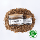 Two jars of Texas Salt Co. Cowboy Salt®—one large, one small—crafted with garlic rosemary sea salt, rest on coarse salt. At the bottom right is a green International Flavor Awards badge against a white background.