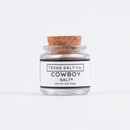 A small glass jar with a cork lid labeled Texas Salt Co. Cowboy Salt®, net weight 0.5 oz (14g), features premium Texas finishing salt from Texas Salt Co., shown against a plain white background.