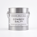 An 80 oz (2286g) metal pail of Texas Salt Co. Cowboy Salt®, with a minimalist black and white label, holds bold Texas finishing salt smoked over pecan wood. Features a handle for easy carrying.