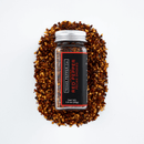 A glass jar labeled Texas Salt Co. Pecan Smoked Crushed Red Pepper rests on a pile of its pecan smoked crushed red pepper, artfully arranged to showcase this bold Texas-made seasoning from Texas Salt Co.