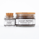 Two jars of Texas Salt Co. Ghost Pepper Smoked Salt—crafted with Naga Jolokia. The small jar has a cork lid; the large, a wooden lid. Both feature white labels with black text describing this fiery sea salt and displaying the net weight.