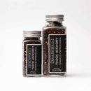 Two glass jars of Texas Salt Co. Thick Hickory Smoked Peppercorn—one small (2 oz) and one large (4.5 oz)—with silver lids and black labels, displayed on a white background.