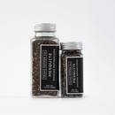 Two clear glass jars of Texas Salt Co. Mesquite Smoked Peppercorn, one 4.5 oz and one 2 oz, sit side by side on a white background. Both have black labels showcasing this bold Texas Salt Co. smoked seasoning.