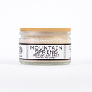 A clear glass jar with a wooden lid holds mineral-rich salt. The label, in bold black and white, reads "Texas Salt Co. Mountain Spring Peruvian Salt, Net Wt 5oz (142g).