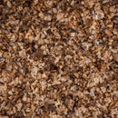 A close-up of coarse, jagged flakes in brown and tan shades highlights the rustic texture of Texas Salt Co. Pecan Smoked Salt by Texas Salt Co., resembling raw bran cereal or a smoky, grainy food.