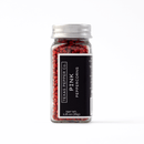 A clear glass jar with a silver lid contains whole pink peppercorns. Its black label reads "Texas Salt Co. Pink Peppercorn," showing the net weight as 1.25 oz (35g). This floral spice is displayed against a white background.