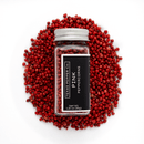 A 1.25 oz (35g) glass jar of Texas Salt Co. Pink Peppercorn rests on a pile of whole pink peppercorns, highlighting their floral spice notes against a white background.