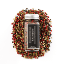 A glass jar labeled Texas Salt Co. Rainbow Peppercorn is surrounded by premium red, black, white, and green peppercorns on a white background, showcasing the vibrant five-pepper blend by Texas Salt Co.