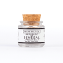 A small glass jar with a cork lid labeled "Texas Salt Co. Republic of Senegal African Salt" contains mineral-rich salt from Senegal, Net Wt .75oz (21g), shown against a white background.
