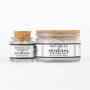 Two glass jars of Texas Salt Co. Republic of Senegal African Salt are shown side by side: the smaller jar is 0.75 oz (21g) and the larger jar is 5.5 oz (156g), each with a cork lid.