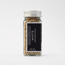 A clear glass jar with a silver lid is filled with Texas Salt Co. White Peppercorns. The black label displays the brand name and product, listing the net weight as 2.5 oz (71g). The background is plain white.