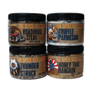 Four jars of The Spice Guy Thyme Traveler's Toolkit are stacked in pairs. Flavors—Roadhouse Steak, Truffle Parmesan, Thunder Struck, and Honey Thai Bangkok—offer global inspiration with unique artwork and bold typography.