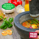 A close-up of a mortar and pestle crushing colorful spices and herbs—including Rico Rico Habanero Chile Powder Shaker for that hot spice kick—on a wooden surface, with a basil sprig nearby. The Authentic Mexican Flavor and Rico Rico logos appear on the image.
