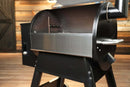 A stainless steel Pimp My Grill® Bodyguard Stainless Steel Grease & Paint Protector installed inside the main chamber of a black pellet grill.