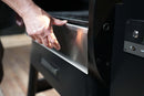 A hand installs a Pimp My Grill® Bodyguard Stainless Steel Grease & Paint Protector onto the front edge of a Ridgeline XL pellet grill.