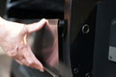 A hand slides a Pimp My Grill® Bodyguard Stainless Steel Grease & Paint Protector into the side of a black Ridgeline XL grill.