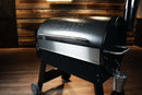 A black pellet grill featuring a Pimp My Grill® Bodyguard Stainless Steel Grease & Paint Protector attached to the front of the lid as a grease shield.