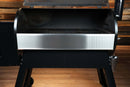 A horizontal stainless steel Pimp My Grill® Bodyguard Stainless Steel Grease & Paint Protector for Traeger Pro 34 / Century 885 / Texas attached to the front of an open pellet grill.