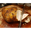 A SpitJack 6 Inch Beef Brisket Trimming and Boning Knife and 11″ Slicing Knife Bundle from SpitJack expertly slices through a seasoned, roasted turkey breast on a wooden cutting board. The meat is juicy and tender with a crispy, peppery crust.