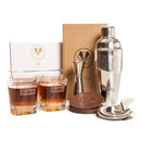 A Swanky Badger Whiskey Essentials Bundle including two personalized whiskey glasses, a cocktail shaker, a jigger, a Hawthorne strainer, and leather coasters arranged in front of their product boxes.