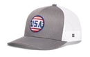 The Haka Hat USA Stripes Trucker Hat by Haka Hat is a gray and white mesh trucker hat featuring a circular red, white, and blue USA logo on the front; a small square logo tag accents the left side of the mesh for a classic patriotic look.