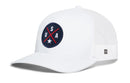 The Haka Hat USA X Trucker Hat by Haka Hat is a white mesh snapback featuring a navy circular patch with “USA” and a star crossed by two red lines. This patriotic blue-red-white America hat also includes a small rectangular tag with a black geometric design on the mesh side.