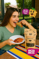 A smiling woman enjoys a taco and holds a bowl of food beside a bag of Rico Rico Ancho Dried Chiles – Sweet & Smoky Mexican Peppers (Mild Heat) on a colorful tablecloth. Text bubbles and a chile emoji highlight the authentic Mexican flavor these Rico Rico chiles bring to her meal.