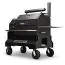 The Yoder Smokers YS640S Competition Pellet Grill features a large black design with wheels, chimney, front shelf, side tray, stainless steel shelves, and the Yoder Smokers brand name displayed on the lower front panel.