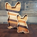 The French Bulldog Wood Tray by Two Acre Woodworks features two handcrafted trays with large ears in different wood tones, displayed on a brown surface before a rustic wood wall—a perfect decorative organizer gift for dog lovers.