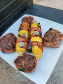 Grill Pinz Bacon Holders made from stainless steel for securing bacon wraps, stuffed meats, and grilled vegetables shown with bacon wrapped corn