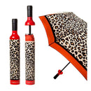 The Vinrella Leopard Print Bottle Umbrella features a compact leopard print design with orange trim. It fits inside a matching wine bottle-shaped case for stylish, no-drip, on-the-go use, shown open and closed.