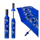 The Vinrella Spot On Dog Bottle Umbrella has a blue canopy with white, yellow, and black dogs. It features a no-drip design and folds into a matching blue wine bottle-shaped case with the same playful dog pattern.